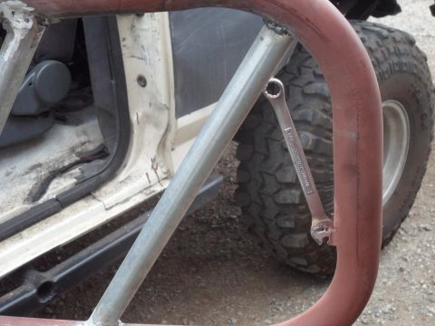1991 Ford Bronco - Wrench attached to roll cage tubing inside a vehicle. The door is open, revealing the interior and a tire.