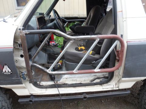 1991 Ford Bronco - The interior of a vehicle shows a custom-welded roll cage, with tools visible on the passenger seat.