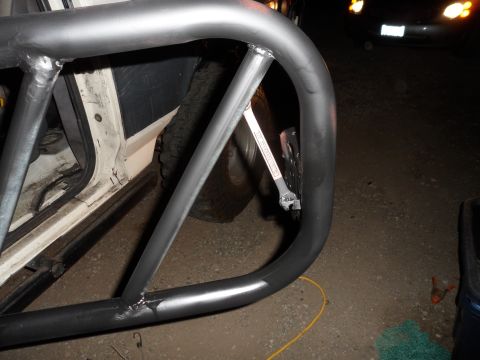 1991 Ford Bronco - A metal roll cage is attached to the side of a white vehicle, obscuring the door and tire.