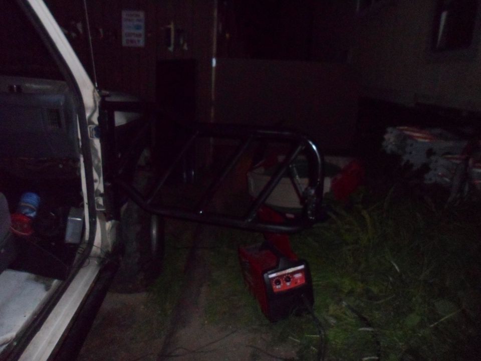 Vehicle door open, showing interior. Roll cage and red generator on grass nearby