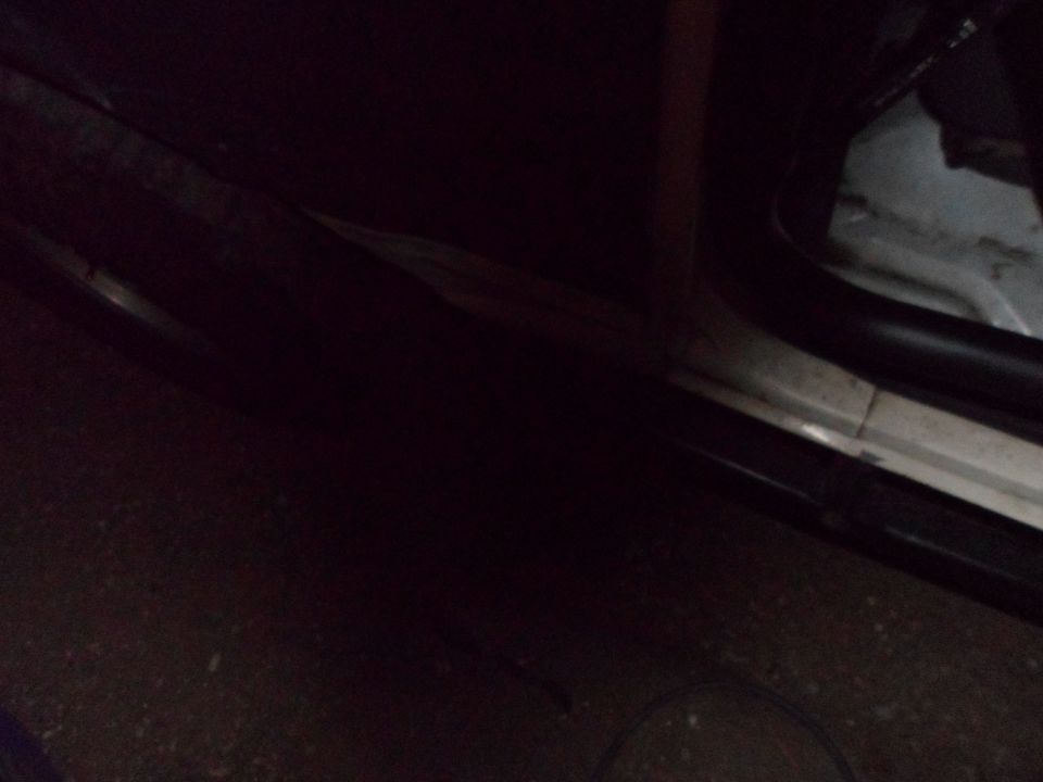 Dark vehicle interior door sill with white trim and black rubber seal. Some dirt visible