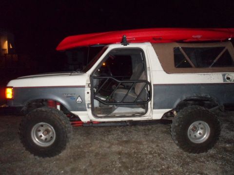 1991 Ford Bronco - Modified 1991 Ford Bronco with off-road tires and a kayak secured to the roof rack.