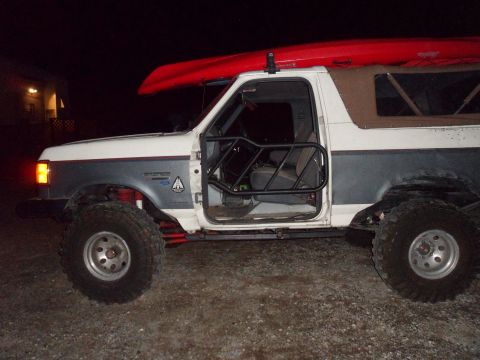 1991 Ford Bronco - This modified Ford Bronco has a custom roll cage and off-road tires, with a kayak secured to its roof.