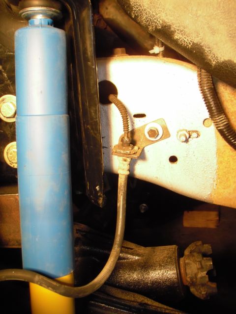 1995 Ford Bronco - Vehicle suspension detail showing a shock absorber and brake line assembly.