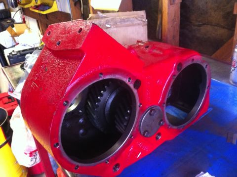 1989 Ford Bronco - A red transfer case housing with internal gears is shown, likely a component for a vehicle drivetrain.