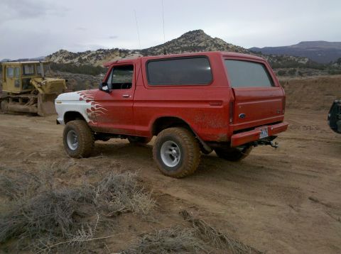 1979 Ford Bronco - This red SUV is parked on a dirt road with a bulldozer in the background.