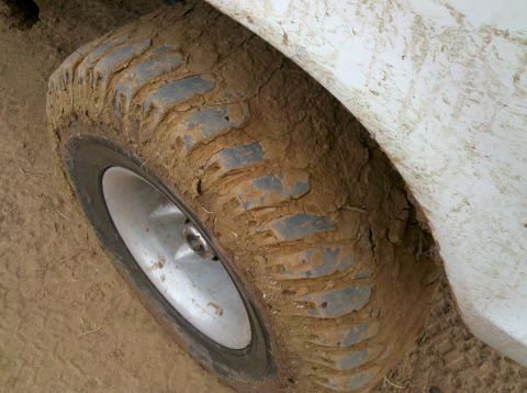 1979 Ford Bronco - A close-up view of a tire and fender covered in mud, suggesting off-road use.