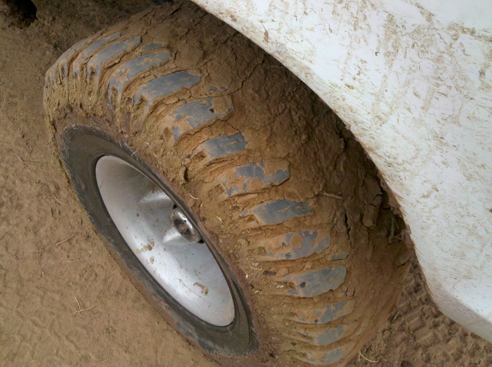Mud-caked tire and fender of an off-road vehicle