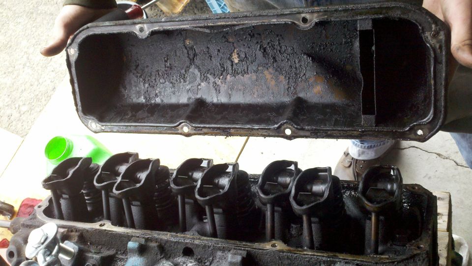 Dirty engine valve cover and cylinder head with visible valve train components