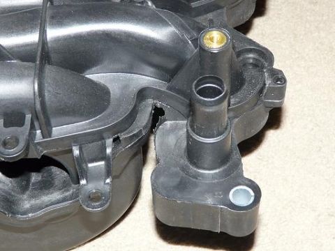 1999 Ford Crown Victoria - This is a close-up of a damaged plastic intake manifold part with hose connections.