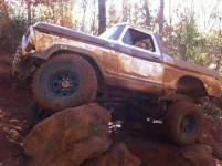 1986 Ford Bronco - This heavily modified 1978 Ford Bronco navigates a rocky, off-road trail, covered in mud.