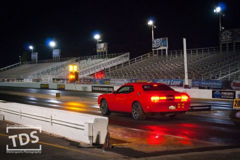 2010 Dodge Challenger - A red 2010 Dodge Challenger is seen from the rear on a drag strip at night, with stadium lights illuminating the scene.