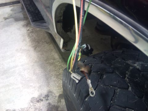 1994 Ford Bronco - Wiring is exposed and dangling near the tire and wheel well of a vehicle.