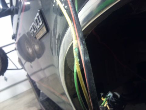 1994 Ford Bronco - A close-up of a Ford Bronco's side panel reveals the emblem and some wiring, suggesting a model from the early 1990s.