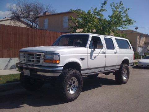 1996 Ford C-350 (Centurion Conversions) - This lifted white SUV, likely a 1992 model, is parked on a residential street.