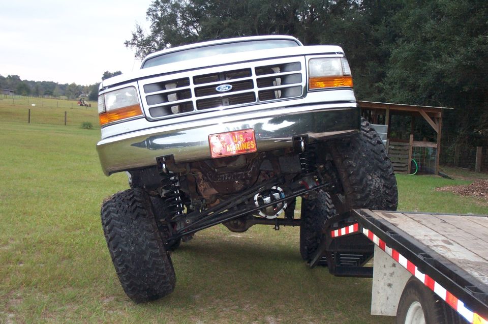Lifted white and green Ford Bronco from the front with articulated solid axle, mud tires, and US Marines plate