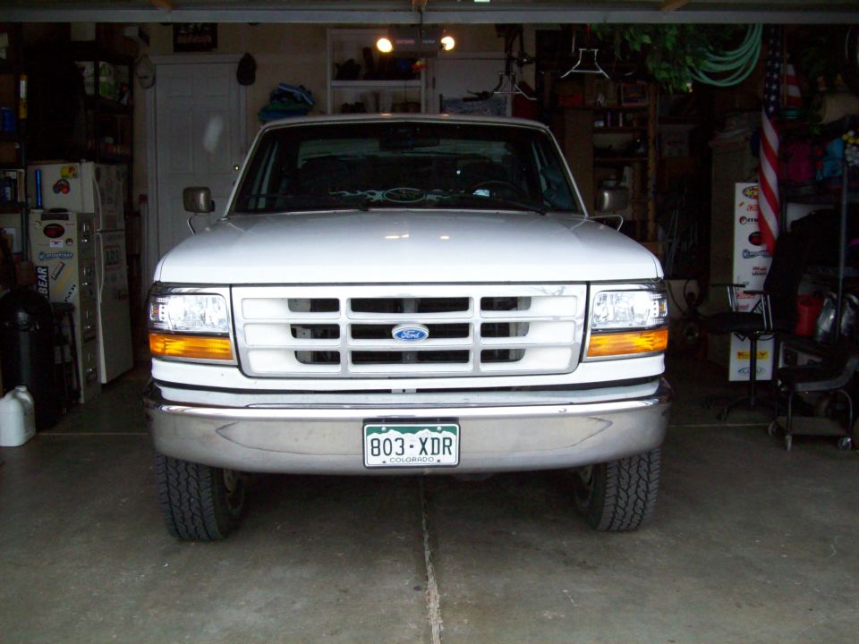 White Ford F-150 truck front view in garage, chrome bumper, clear headlights