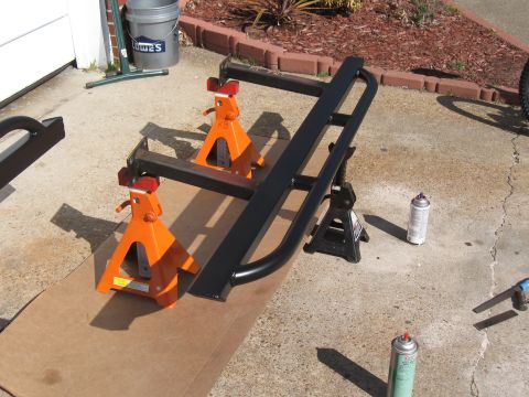 1994 Ford Bronco - Rock sliders are shown on jack stands, ready for installation or modification, with spray paint cans present.