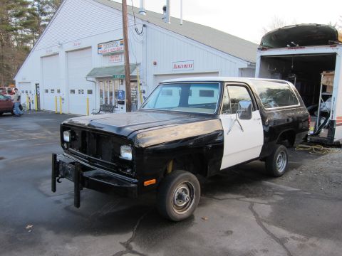 1987 Dodge 1500 - This two-tone SUV, likely from the 1980s, is parked in front of a repair shop.