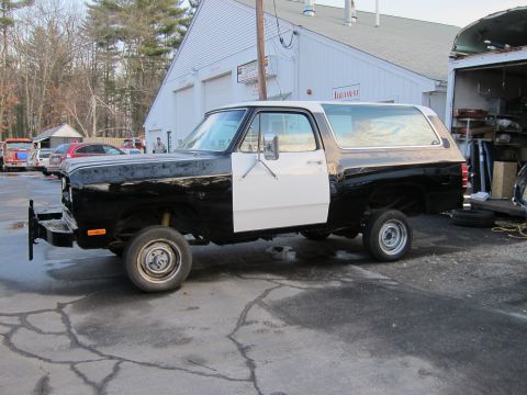 1987 Dodge 1500 - This Dodge Ramcharger is parked outside a garage with a white door and black body panels.