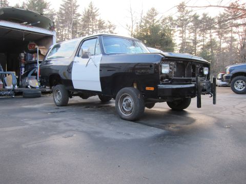 1987 Dodge 1500 - A black and white Dodge Ramcharger is parked outside a garage, missing its grille and headlights.