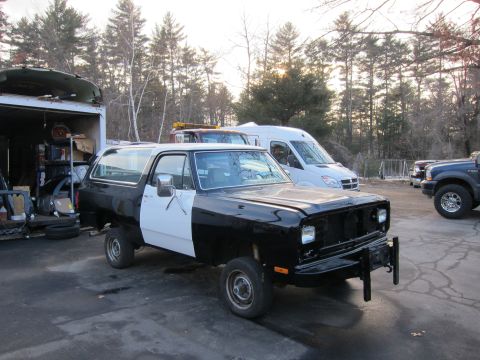 1987 Dodge 1500 - A two-tone Dodge Ramcharger sits in a lot with other vehicles and a storage trailer.