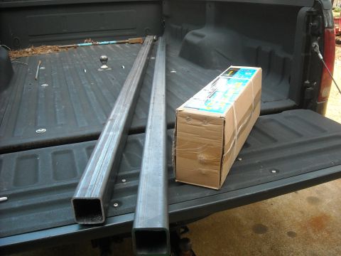 1979 Ford F-150 - Metal bars and a box are loaded into the bed of a pickup truck, which has a fifth wheel hitch.