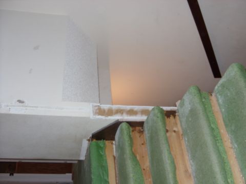 1988 Ford Bronco - The interior of a building shows unfinished walls and exposed wooden beams with green foam insulation.