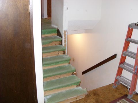1988 Ford Bronco - An interior view of a staircase with worn green carpet and a ladder nearby.