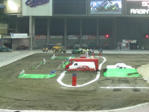 1986 Ford Bronco - An indoor arena is set up for a Monster Jam event with various obstacles on the dirt track.