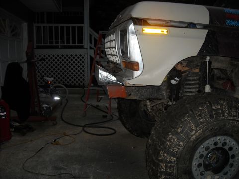 1979 Ford F-150 - The front end of a lifted 1979 Ford F-150 is visible, showing its grille and large off-road tires.