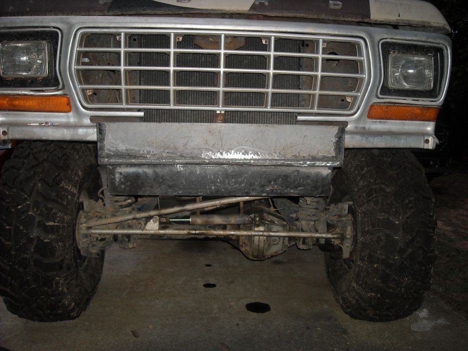 Front of lifted 1970s Ford truck with chrome grille, mud tires, and solid front axle