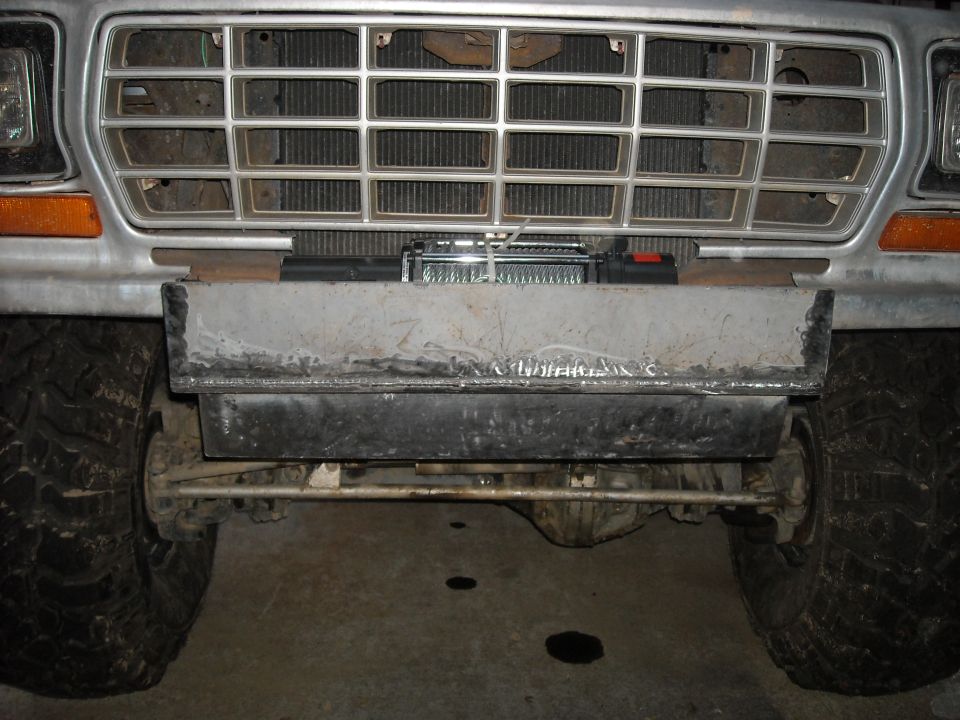 Front of vintage Ford pickup with winch behind grille and custom steel bumper