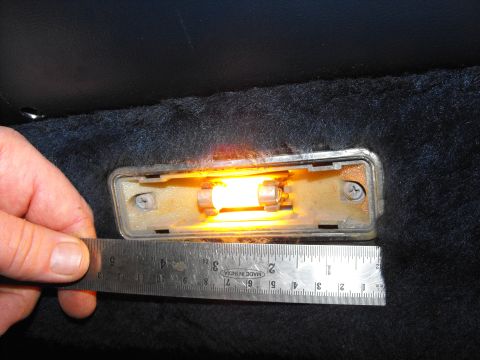 1986 Ford Bronco - A ruler is used to measure the size of an illuminated interior door light assembly.