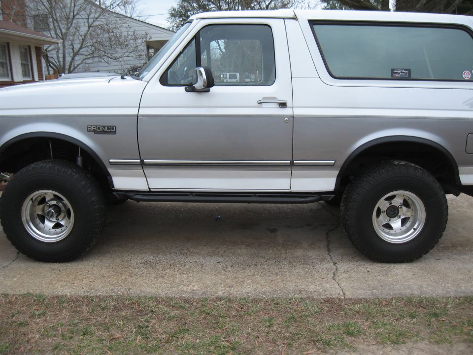 White and silver two-tone 1994 Ford Bronco side view with aftermarket wheels and running boards