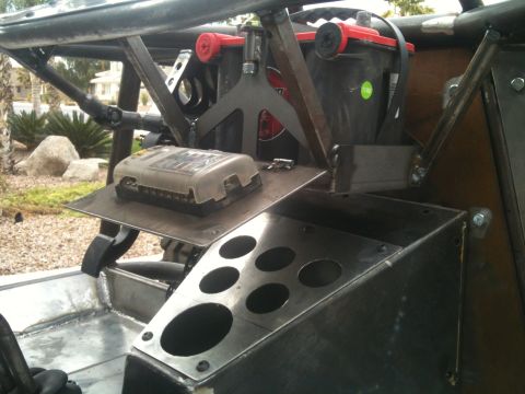 1966 Ford Bronco - The interior of a custom off-road vehicle shows a battery, fuse box, and a panel with multiple circular cutouts.
