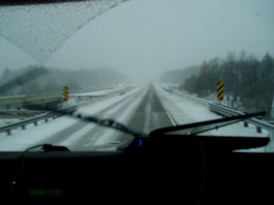 Driving on a highway covered in snow with low visibility