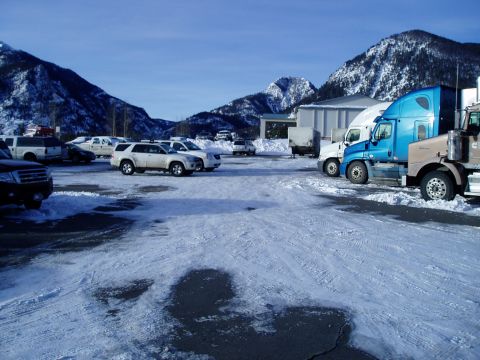 2009 Kenworth T800 - Multiple vehicles, including trucks and SUVs, are parked in a snowy lot with mountains visible.
