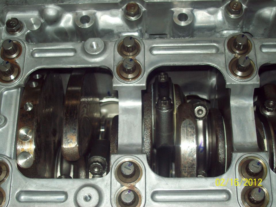 Close-up of crankshaft counterweights and rod caps inside an engine block main girdle