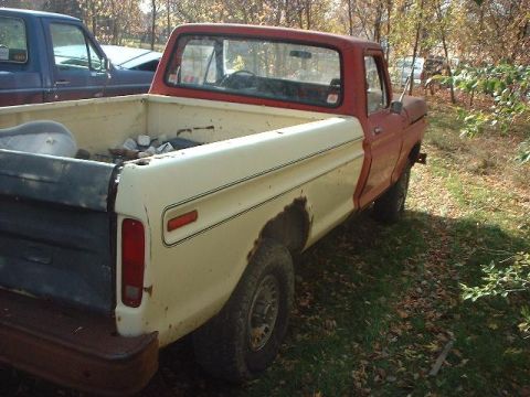 1993 Ford Bronco - A red and white Ford F-Series pickup truck sits in a grassy yard with fallen leaves.