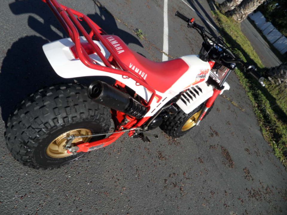 Red and white Yamaha three-wheeler with gold rims and large rear tire