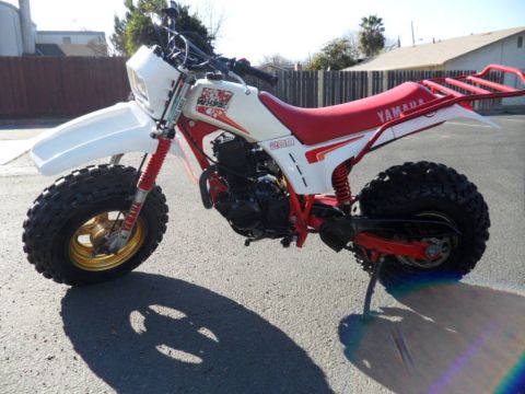 1994 Jeep Cherokee - A white and red Yamaha 200 three-wheeler motorcycle is parked outdoors on asphalt.