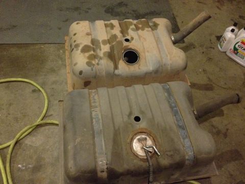 1995 Ford Bronco - Two fuel tanks are shown on a workshop floor, with a yellow hose and oil bottles nearby.