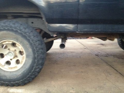 1995 Ford Bronco - Side view of a vehicle's undercarriage, focusing on the exhaust pipe and rear wheel.