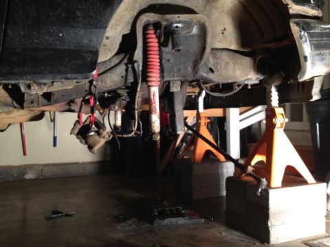 1995 Ford Bronco - Vehicle undercarriage shown with suspension components removed, supported by jack stands.