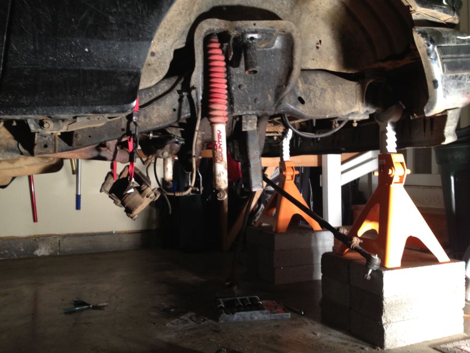 Undercarriage of vehicle on jack stands, red shock absorber visible