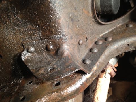 1995 Ford Bronco - This image shows heavily rusted frame and suspension components, with visible rivets and a shock absorber.