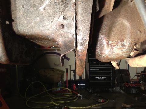 1995 Ford Bronco - Close-up view of the rusty undercarriage of a vehicle, with tools and equipment in the background.