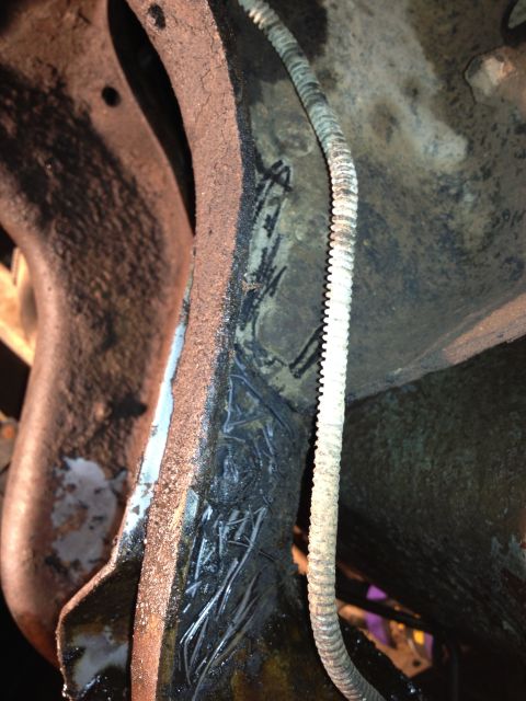 1995 Ford Bronco - Close-up view of a vehicle's frame and a wire conduit, showing rust and markings.