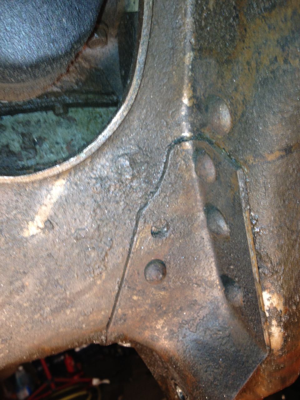 Close-up of cracked and greasy metal frame on a vehicle